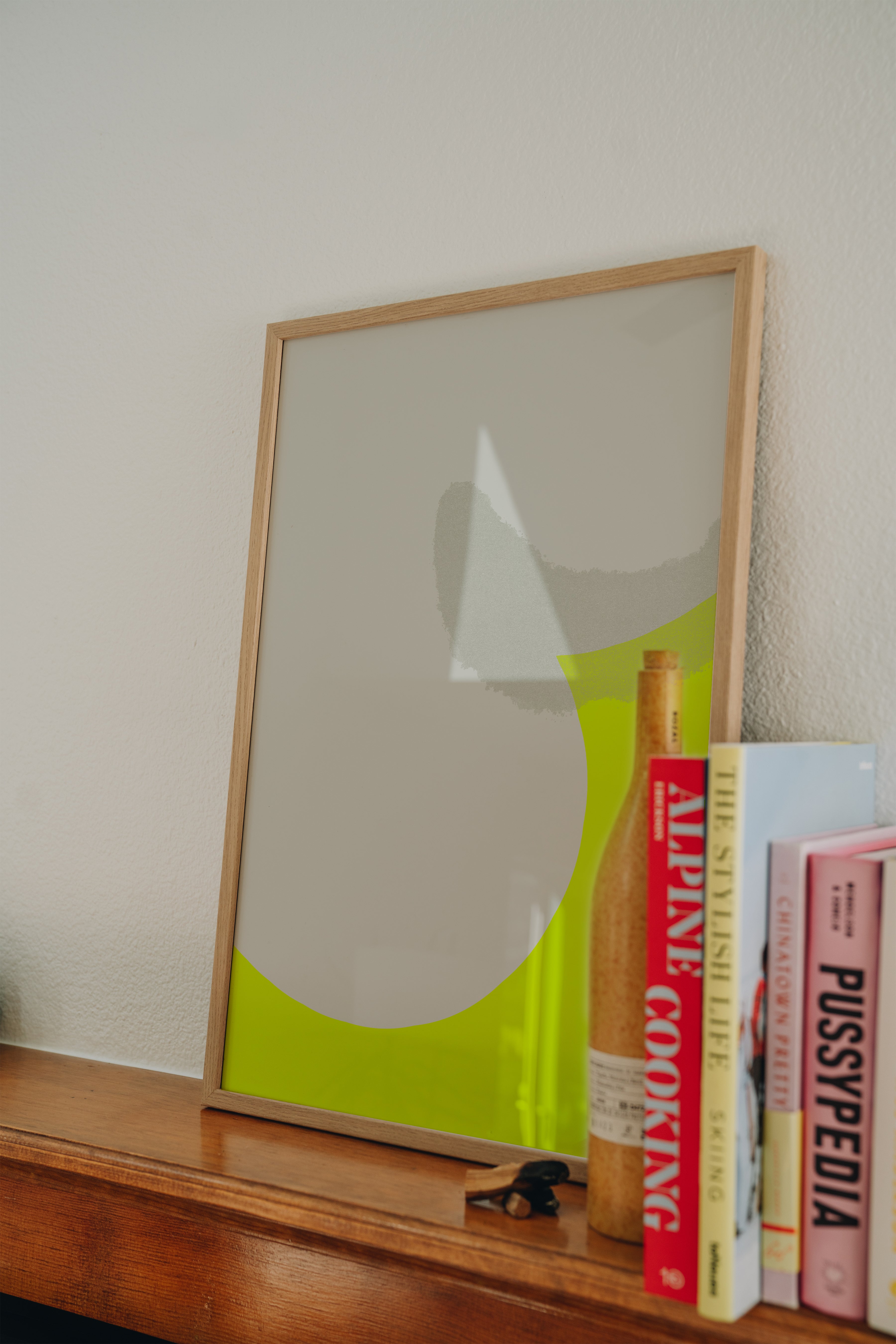 Electric Curve neon green print propped on fireplace mantle next to books, minimalist accent art styling inspiration