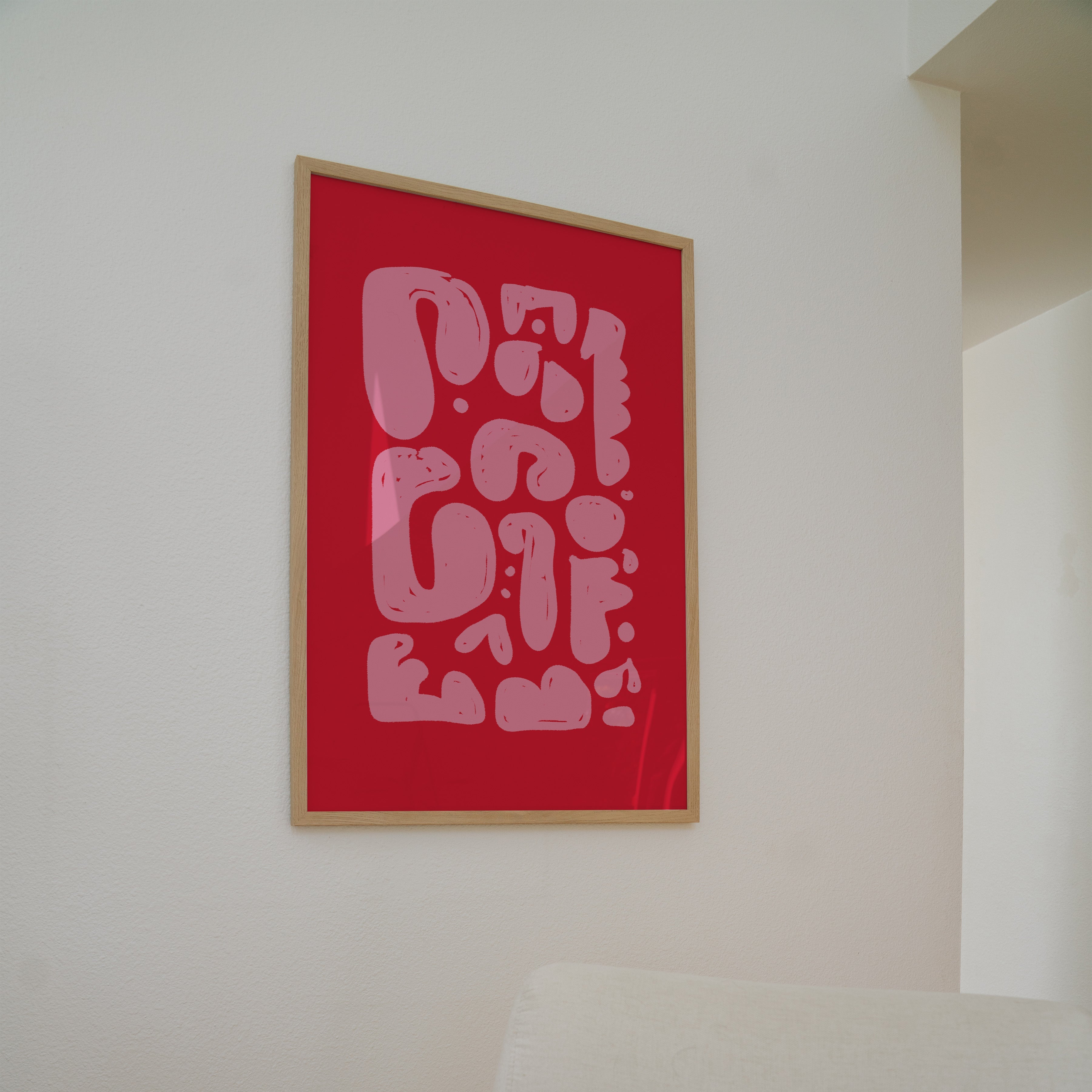 Red framed artwork on a white wall above a beige chair